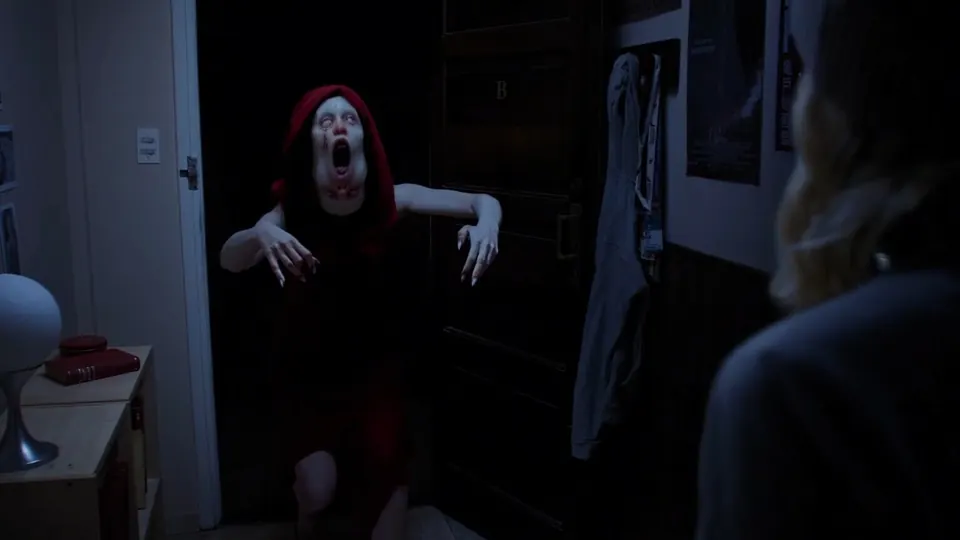Screaming woman lunging forward in a dark hallway