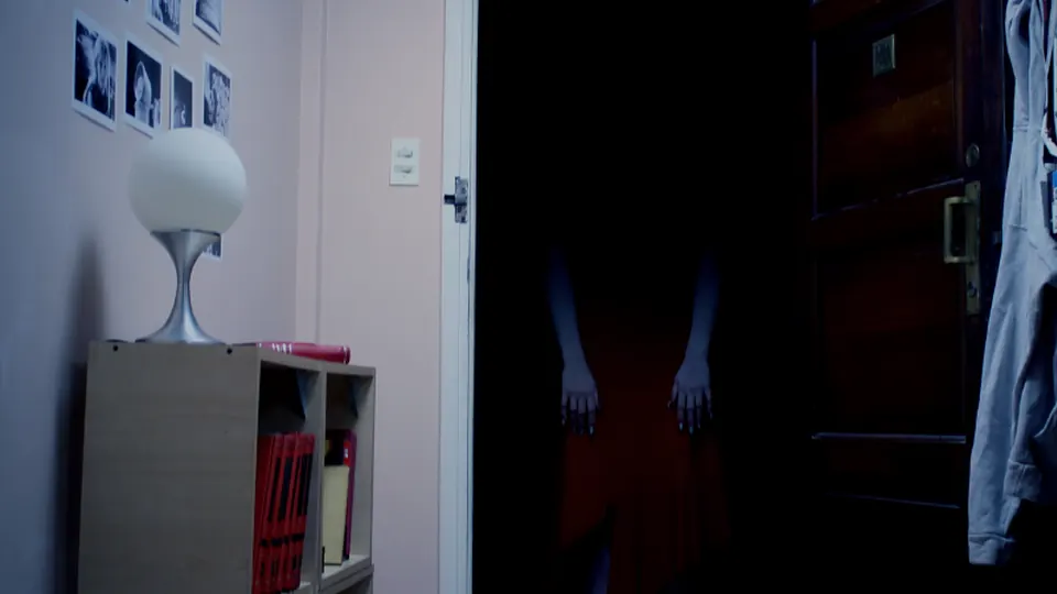 Headless figure in red standing in a dark doorway