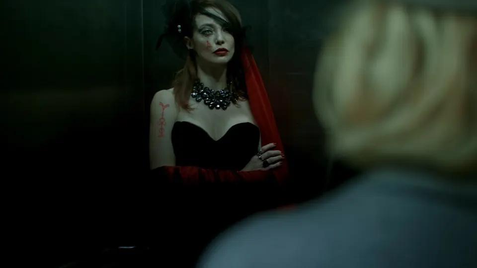 Woman in a red dress standing in green darkness